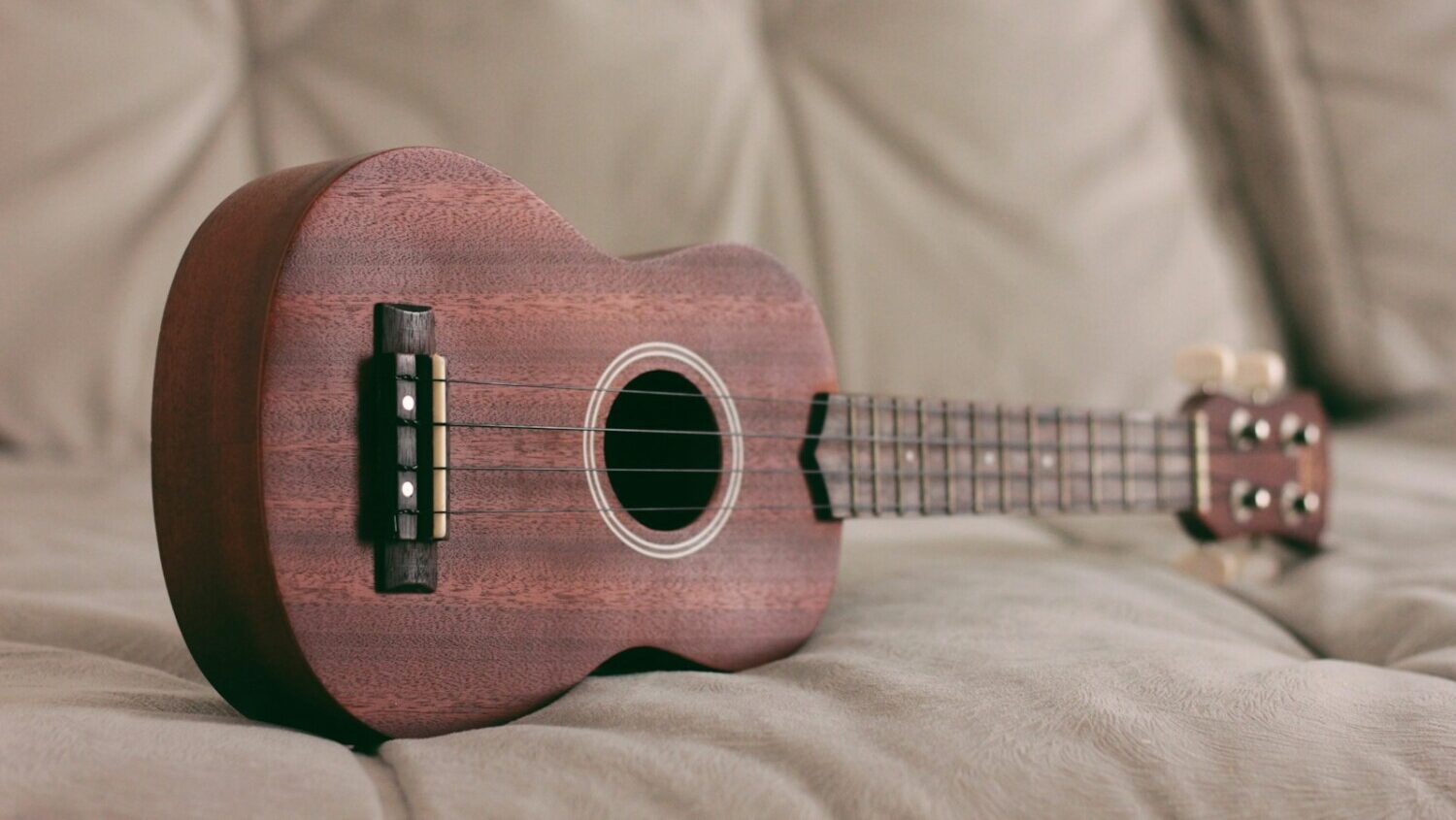 brown ukulele on couch